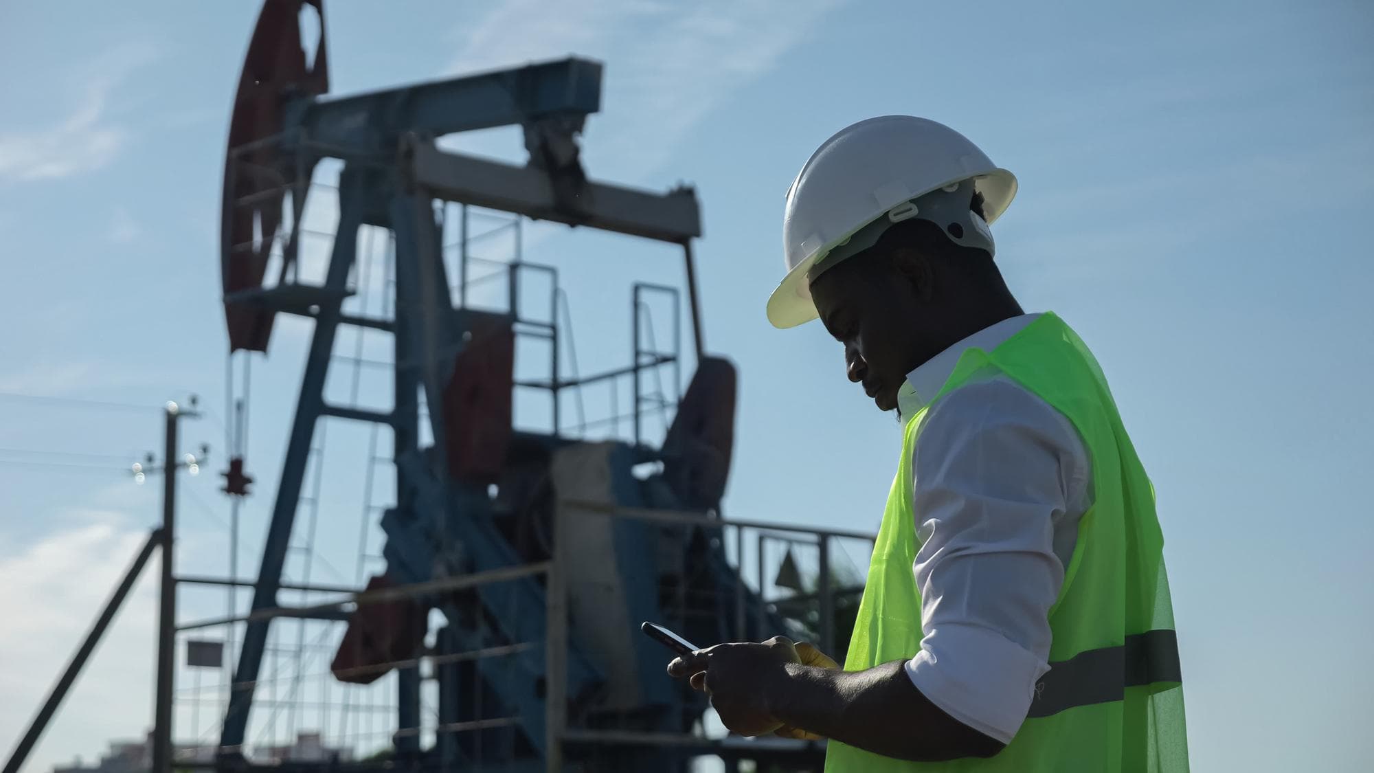 Field engineer checking readings beside an oil pumpjack